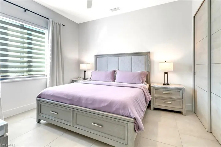 Spacious bedroom with light-toned tile flooring and a ceiling fan