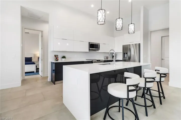 Contemporary kitchen featuring a waterfall island with a white countertop and dark base cabinetry