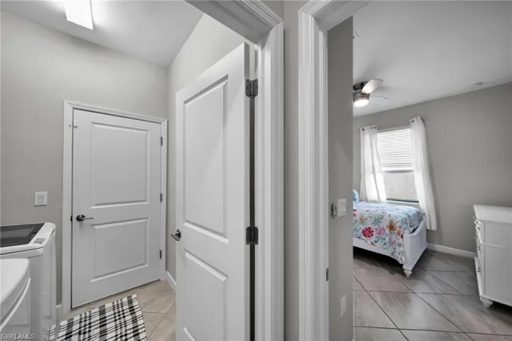 Laundry area with light tile patterned flooring, washing machine and dryer, laundry area, baseboards, and ceiling fan
