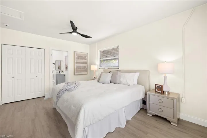 Bedroom with light wood finished floors, ensuite bath, ceiling fan, a closet, and attic access