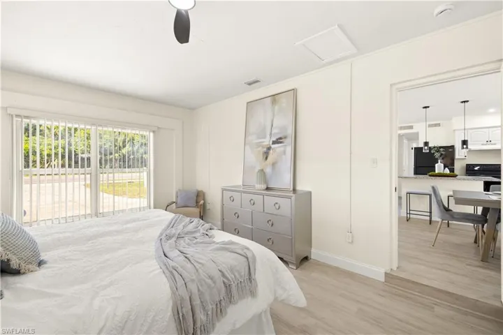 Bedroom featuring freestanding refrigerator, light wood-style floors, access to exterior, attic access, and ceiling fan