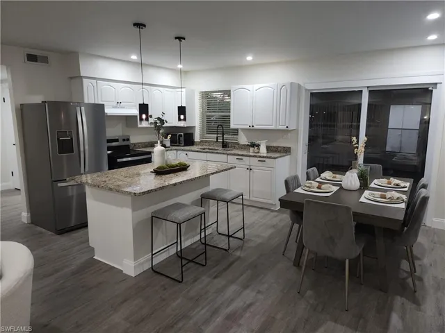 Kitchen featuring appliances with stainless steel finishes, under cabinet range hood, dark wood-style flooring, white cabinets, and recessed lighting
