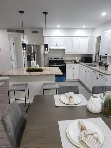Kitchen featuring range, refrigerator, range hood, a kitchen breakfast bar, and a center island