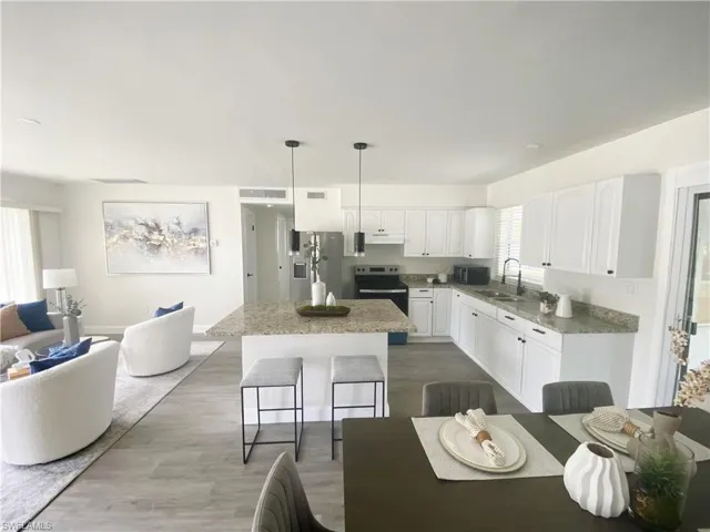 Kitchen featuring appliances with stainless steel finishes, a kitchen island, white cabinetry, and wood finished floors