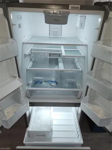 Kitchen view of fridge and wood finished floors
