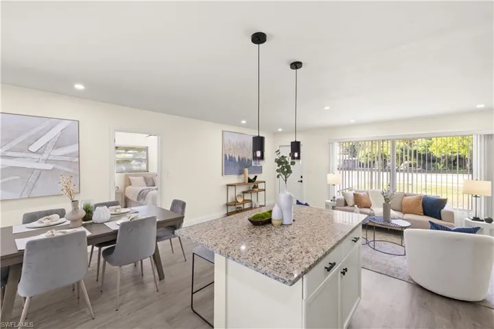 Kitchen featuring light wood finished floors, a kitchen island, open floor plan, white cabinets, and recessed lighting