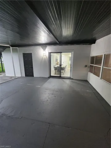Unfurnished room featuring concrete floors, wooden ceiling, and concrete block wall