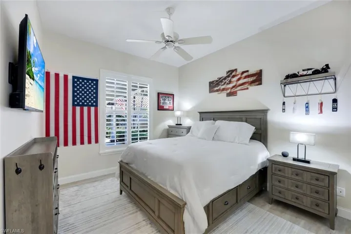Light-filled room featuring wood-finish flooring, a ceiling fan, and window with white plantation shutters