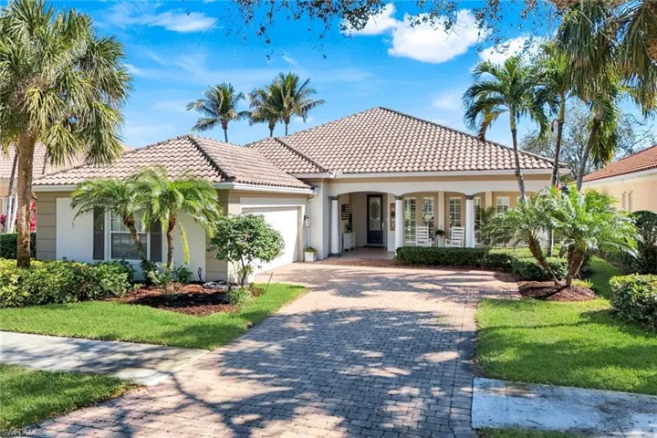 Mediterranean-style residence featuring a tile roof, expansive paver driveway 2 car garage and a covered front entry with columns