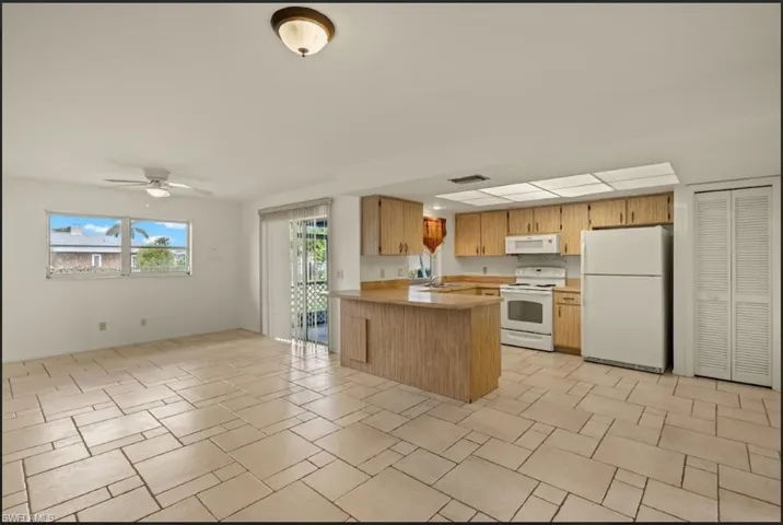 Kitchen with sink, white appliances, kitchen peninsula, and ceiling fan
