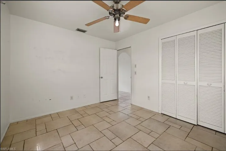 Unfurnished bedroom with ceiling fan and a closet