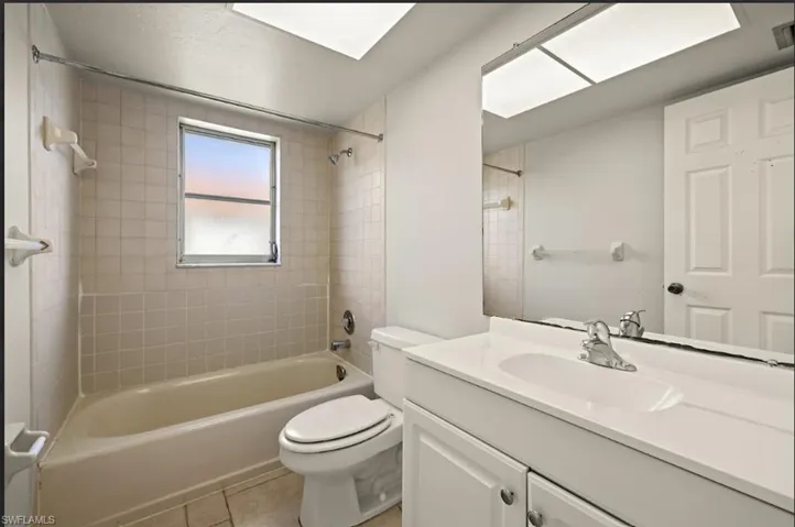 Full bathroom featuring vanity, tile patterned floors, toilet, and tiled shower / bath