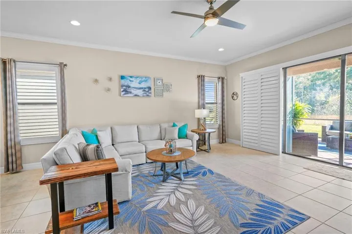 Living area with light tile patterned flooring, ornamental molding, and a ceiling fan