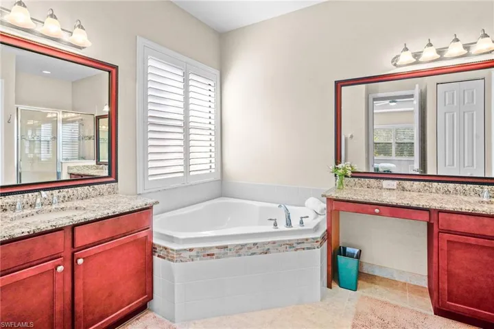 Full bath featuring a bath, two vanities, a shower stall, and plenty of natural light