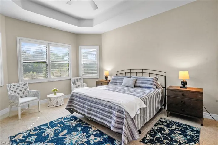 Tiled bedroom featuring a tray ceiling and ceiling fan