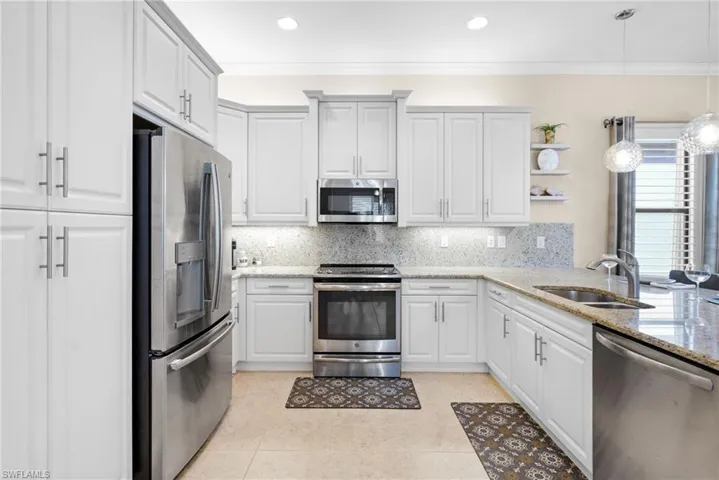 Kitchen featuring stainless steel appliances, hanging light fixtures, light stone counters, open shelves, and backsplash