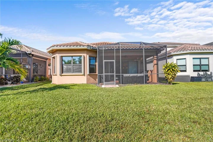 Back of property featuring glass enclosure, stucco siding, a yard, a sunroom, and a tile roof