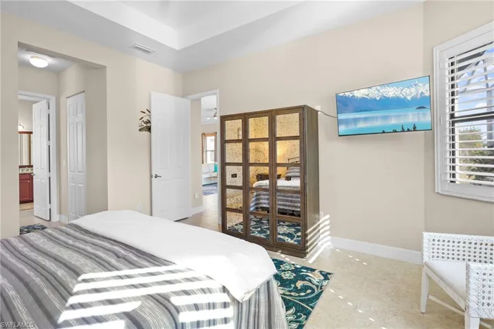 Bedroom with light tile patterned floors and connected bathroom
