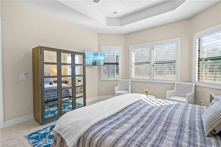 Bedroom with a ceiling fan, light tile patterned floors, and a raised ceiling