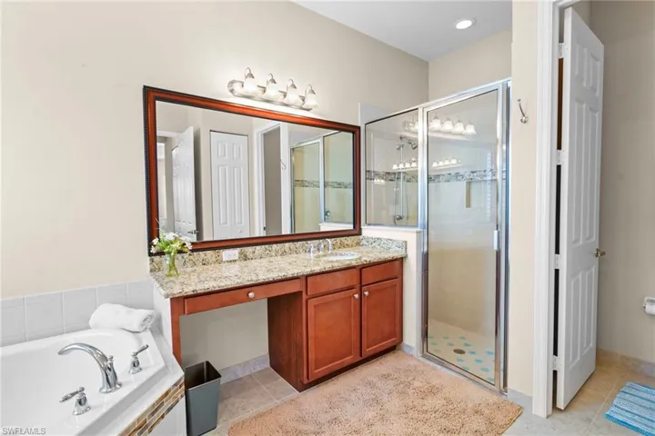 Full bathroom featuring vanity, a shower stall, a bath, and light tile patterned floors