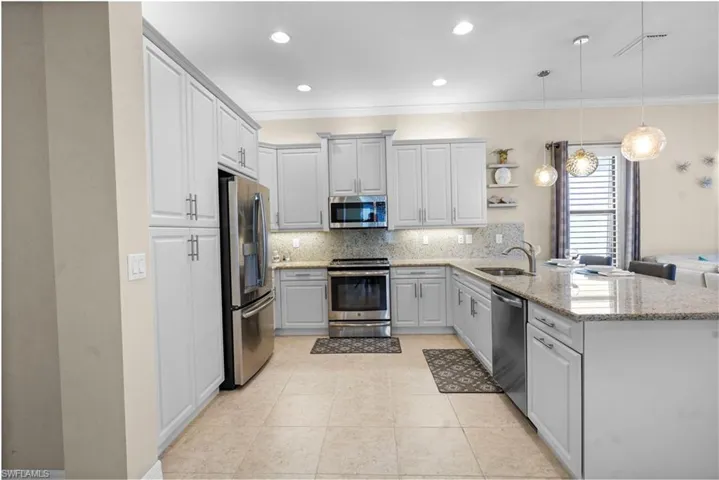 Kitchen with stainless steel appliances, a peninsula, open shelves, pendant lighting, and decorative backsplash