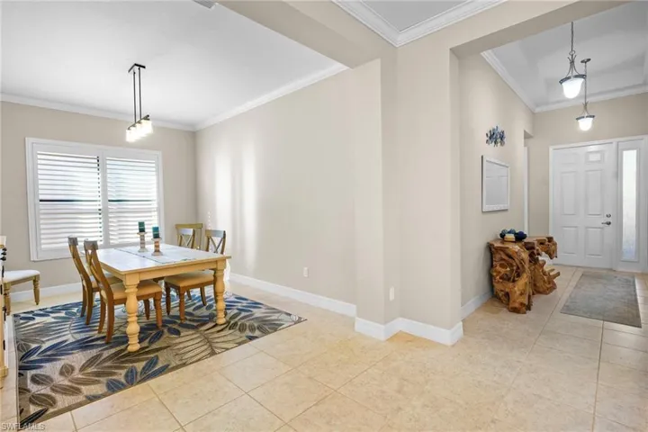 Dining area with crown molding and light tile patterned floors