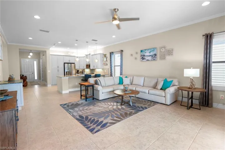 Living room with crown molding, recessed lighting, ceiling fan, and light tile patterned floors