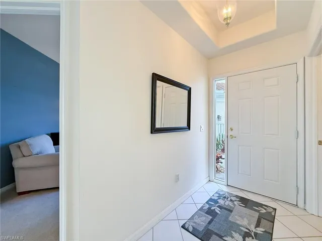Foyer entrance with baseboards, a tray ceiling, and light tile patterned floors