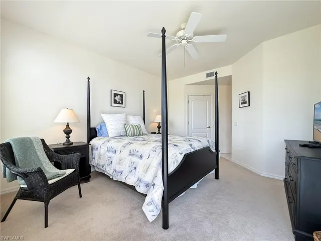 Bedroom with visible vents, baseboards, light colored carpet, and ceiling fan