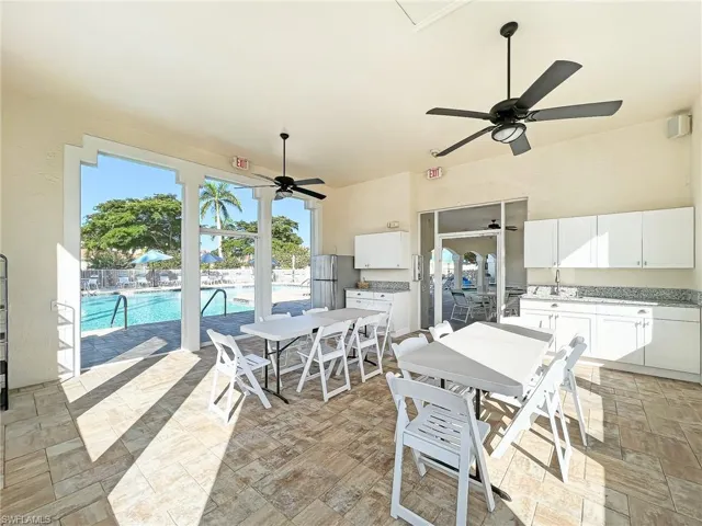 View of patio / terrace with a community pool, a ceiling fan, fence, exterior kitchen, and outdoor dining area