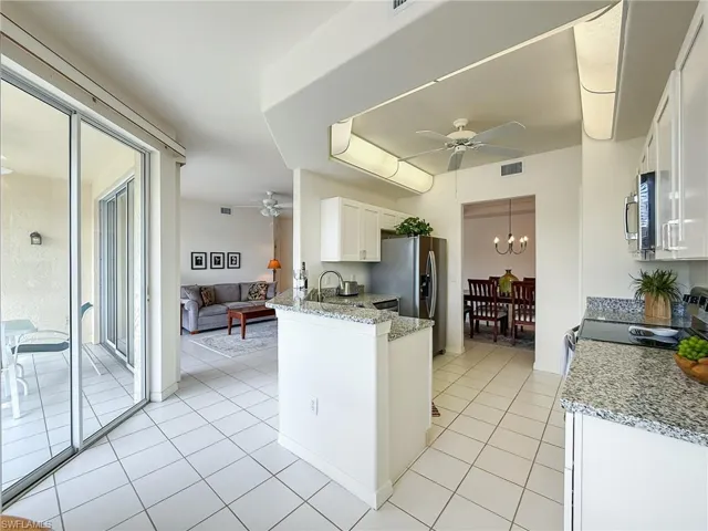 Kitchen featuring a peninsula, white cabinets, ceiling fan with notable chandelier, and appliances with stainless steel finishes