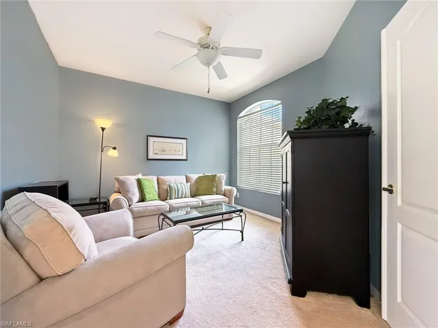 Living area featuring light carpet, baseboards, and ceiling fan
