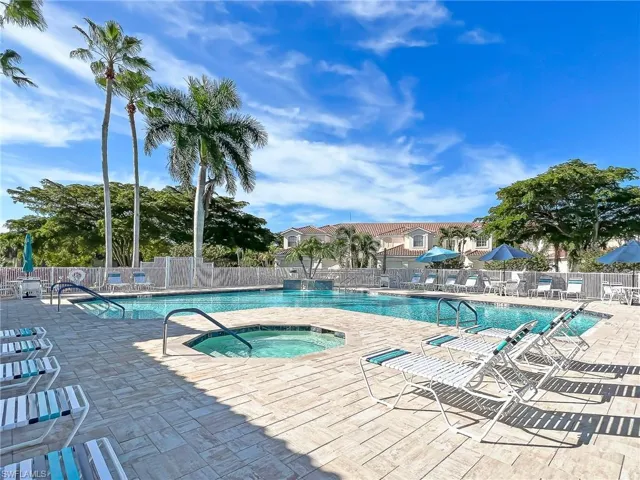 Community pool with a patio, fence, and a hot tub