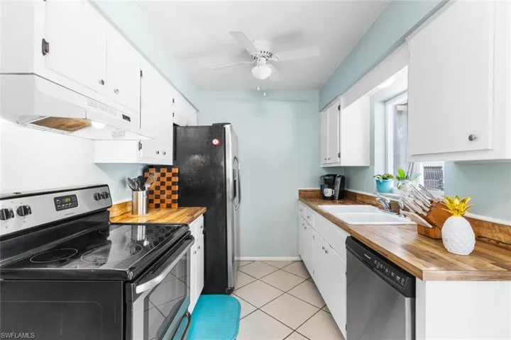 Kitchen featuring butcher block countertops, appliances with stainless steel finishes, sink, and ceiling fan