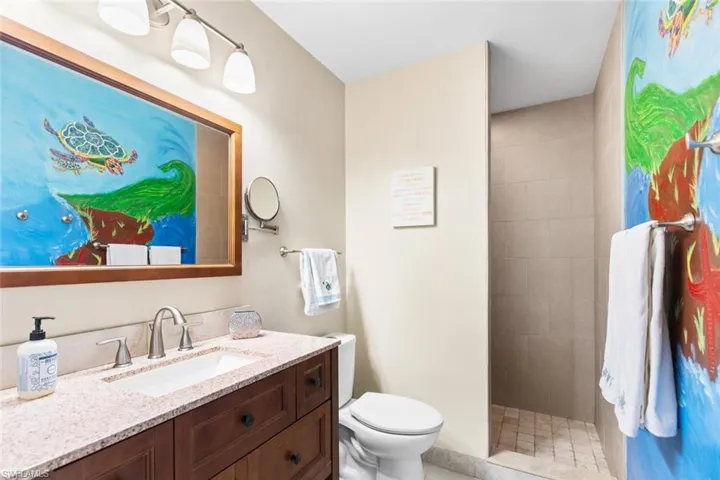 Bathroom featuring tiled shower, vanity, and toilet