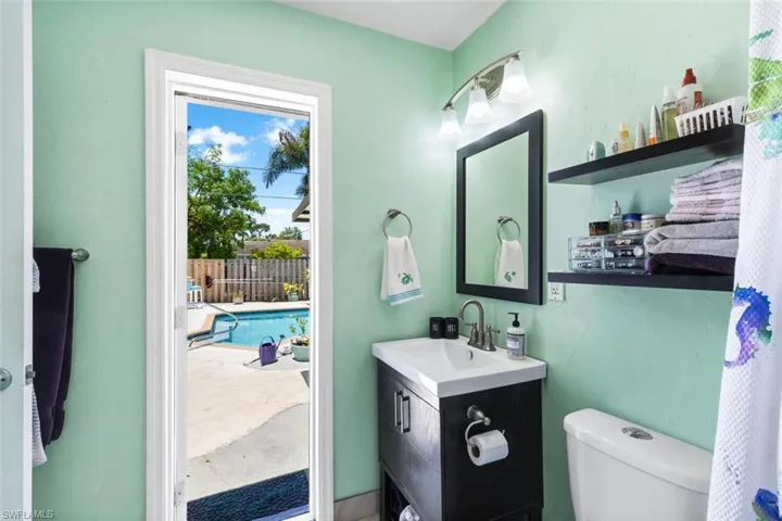 Primary Bathroom featuring toilet and vanity with entrance to pool and backyard