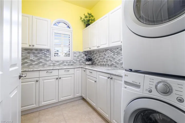 SPACIOUS LAUNDRY ROOM WITH LOADS OF CABINETS (WITH A LAZY SUSAN CABINET!), GRANITE COUNTERTOPS, UTILITY SINK, FULL-HEIGHT TILED BACKSPLASH.  STACKING WASHER AND DRYER.