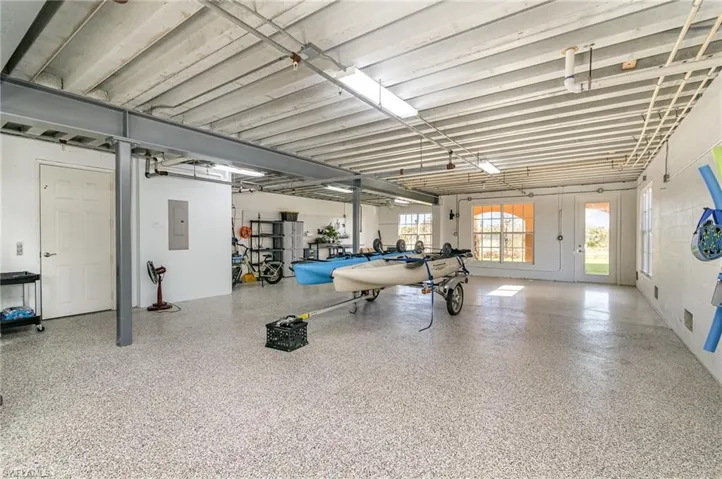 GIGANTIC GARAGE WITH EPOXY FLOORING.  DOOR TO LEFT LEADS INTO HOME; REPLACED IN 2023.  DOOR AT REAR LEADS TO LOGGIA; REPLACED IN 2023.  IMPACT RESISTANT WINDOWS.
