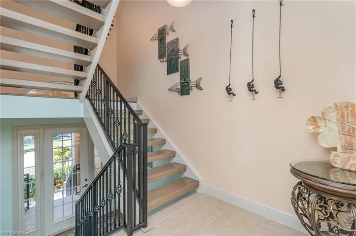VIEW SHOWING UNIT ENTRANCE WITH DIVIDED WINDOWS AND SIDELIGHTS.  TILE FLOORS. HARDWOOD STAIRS.  STAIRS UP LEAD TO MAIN LIVING AREA.  STAIRS DOWN LEAD TO GARAGE.