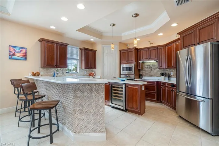 SPACIOUS KITCHEN.  STONE-FACED BREAKFAST BAR.  QUARTZ COUNTERTOPS.  QUARTZ-TOPPED ISLAND WITH BEVERAGE COOLER AND STORAGE.  RECESSED LIGHTING AND PENDANT LIGHTING.