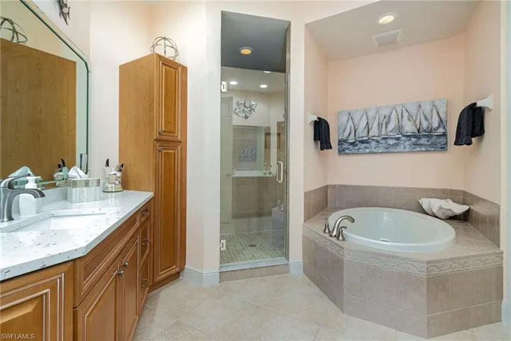 EAST-FACING EN-SUITE BATH WITH SOAKER TUB WITH TILED SURROUND, WALK IN SHOWER AND DUAL VANITIES WITH QUARTZ COUNTERTOPS.