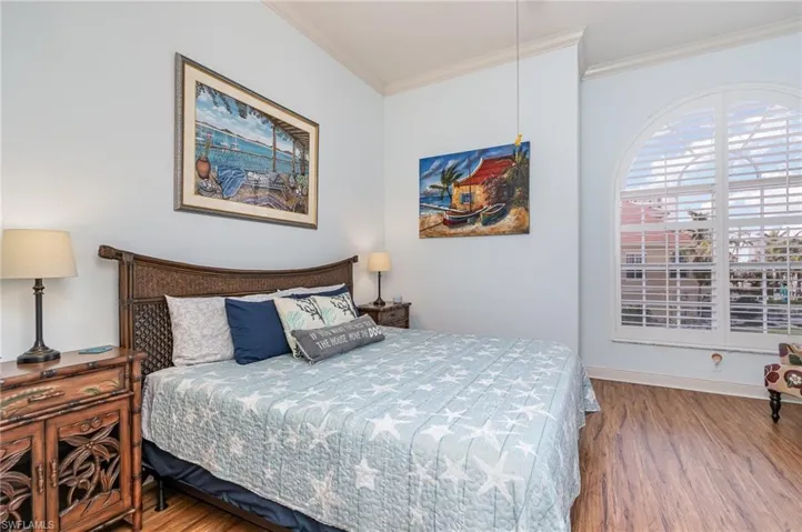 WEST-FACING GUEST SUITE.  ARCHED WINDOW WITH PLANTATION SHUTTERS.  WOOD-LOOK LAMINATE FLOORING.  CROWN MOLDING.