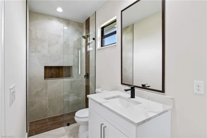 Bathroom featuring vanity, toilet, tile patterned floors, and a shower with door