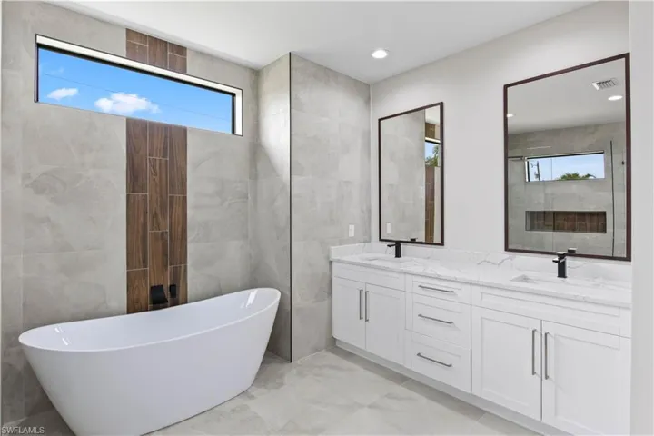 Bathroom with plenty of natural light, tile walls, dual bowl vanity, and tile patterned flooring