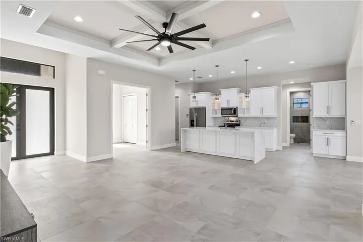 Kitchen featuring beamed ceiling, appliances with stainless steel finishes, light tile patterned floors, and a tray ceiling