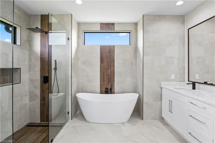 Bathroom with vanity, separate shower and tub, tile patterned flooring, and tile walls