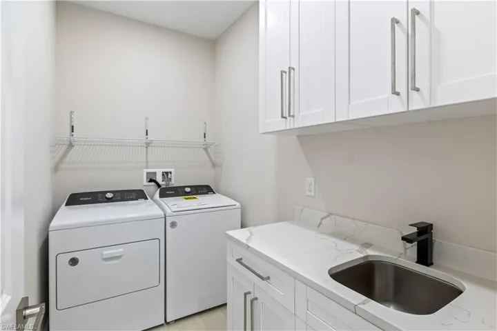 Washroom featuring cabinets, washing machine and dryer, and sink