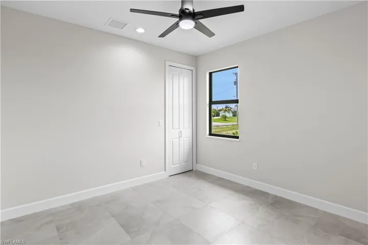 Empty room with light tile patterned floors and ceiling fan