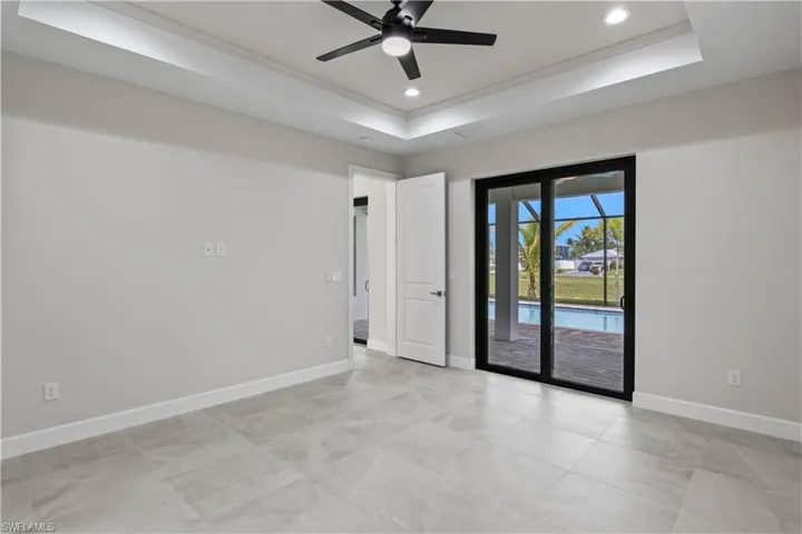 Tiled spare room featuring ceiling fan and a tray ceiling