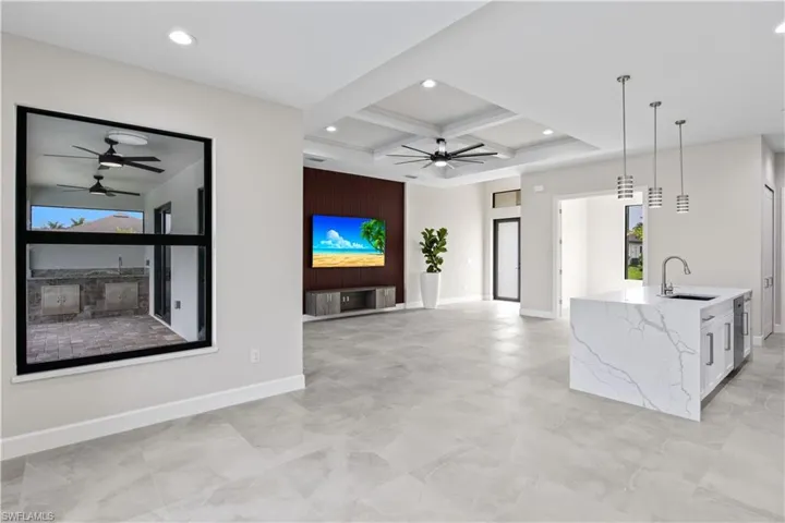 Unfurnished living room with beamed ceiling, sink, coffered ceiling, and ceiling fan